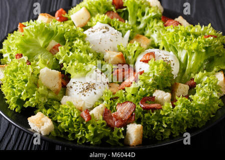 French Lyons Lyonnaise salad with lettuce, croutons and poached eggs close-up on a plate on the table. horizontal Stock Photo