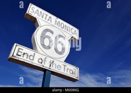 The sign marking the western terminus of historic Route 66 stands on the Santa Monica Pier in California against a brilliant blue sky. Stock Photo