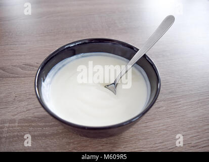 Ceramic bowl of white yogurt isolated on wooden background and spoon with yogurt view from above, plain yoghurt. yogurt. yoghurt Stock Photo
