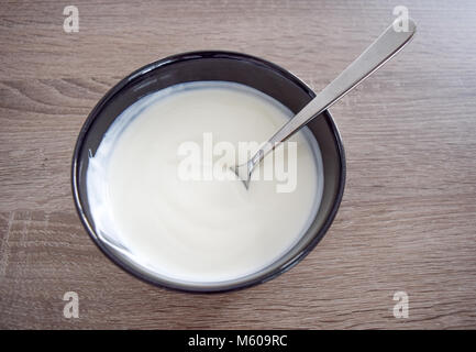 Ceramic bowl of white yogurt isolated on wooden background and spoon with yogurt view from above, plain yoghurt. yogurt. yoghurt Stock Photo