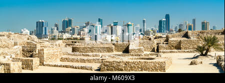 Ruins of Bahrain Fort with skyline of Manama. A UNESCO World Heritage Site Stock Photo