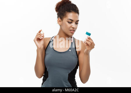 Healthy and healthcare concept - portrait of beautiful sporty African American holding bottle of supplementary bottle. Isolated on white studio background. Stock Photo