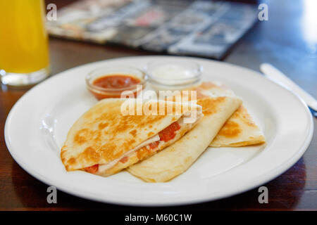 Quesadilla with chicken and tomatoes, two sauces from tomatoes and sour cream. Low key. Side view. Stock Photo