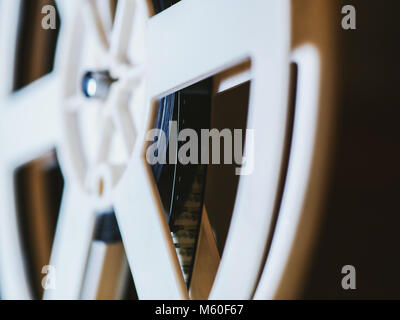 Front view of an old-fashioned antique Super 8mm film projector, projecting a beam of light in a dark room next to a stack of unraveled film reels. Stock Photo