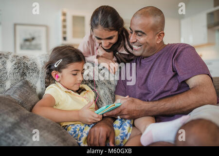 Father and his two daughters using and looking at the digital tablet and laughing. Stock Photo