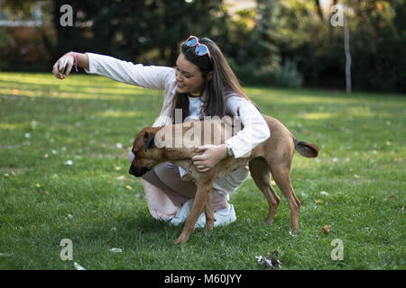 Young woman taking a selfie with her pet dog in the park with smartphone Stock Photo