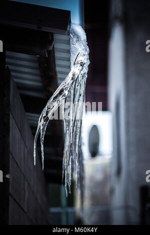 Crooked icicle hanging from a roof Stock Photo