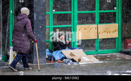 Brighton, UK. 27th Feb, 2018. A homeless man tries to stay warm in a doorway during a snow shower in Brighton today as the 'Beast of the East' snow storms spread across Britain today with more snow and freezing weather forecast for the rest of the week Credit: Simon Dack/Alamy Live News Stock Photo