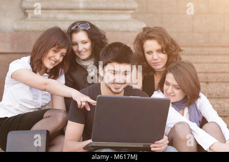 group of students discussing the information with the laptop. Stock Photo