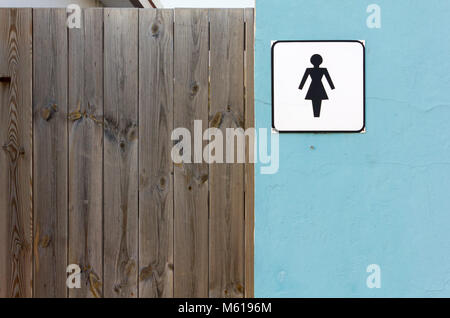 Ladies toilet sign on an exterior wall next to a wooden door Stock Photo
