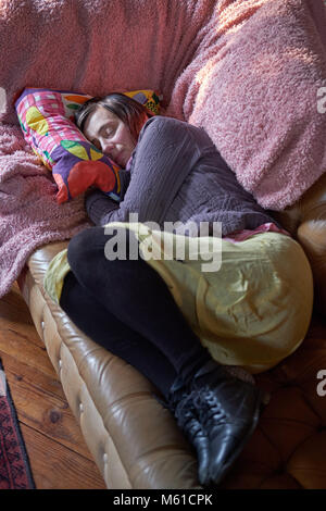 A tired middle-aged woman asleep on a sofa. Stock Photo