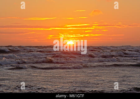 Warm orange sunset on slightly cloudy sky over the baltic sea, seen from the beach of Liepaja, Latvia Stock Photo
