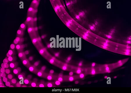 LED violet light string spiral over black pillar in dark night club Stock Photo