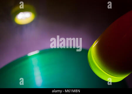 Red lamp shining on green vinyl record on grey wall in disco Stock Photo