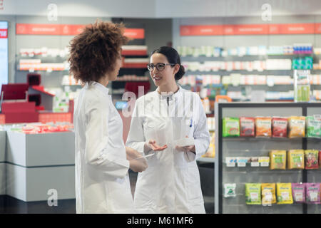 Two friendly colleagues talking while working together in a modern drugstore Stock Photo