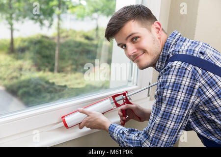 Close-up Of A Young Male Worker Applying Silicone Sealant With Silicone Gun Stock Photo