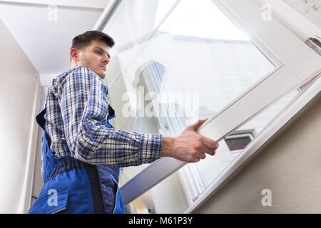 Low Angle View Of A Young Male Repairman Installing Window Stock Photo
