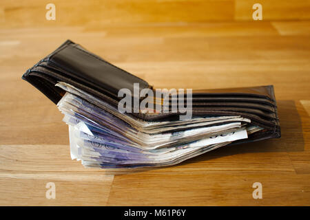 A wallet full of cash, making it difficult to close. Giving the impression of wealth. Stock Photo