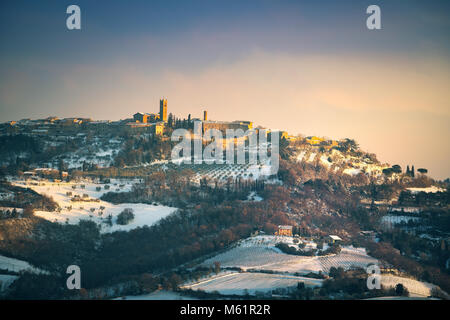 Snow in Tuscany, winter panorama at sunset. Radicondoli village, olive trees and vineyards, Siena, Italy Europe. Stock Photo