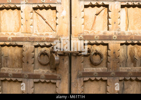 Beautifully carved wooden gate with chain and lock restricting access to the inside. Stock Photo