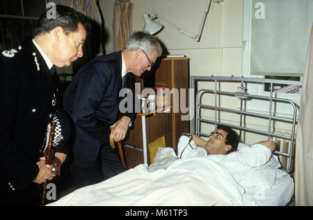 British Home Secretary Douglas Hurd visiting injured police officer in hospital following the Tottenham Riots on Broadwater Farm Estate in 1985. On the left is deputy commissioner of the Metropolitan Peter Imbert who later became Baron Imbert. Stock Photo