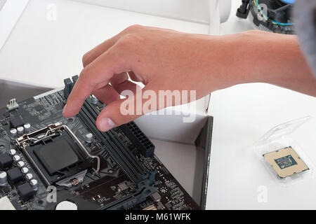 Close up of man hand  openning slot for CPU on PC  motherboard. Processor is in the packaging on the  table. Stock Photo