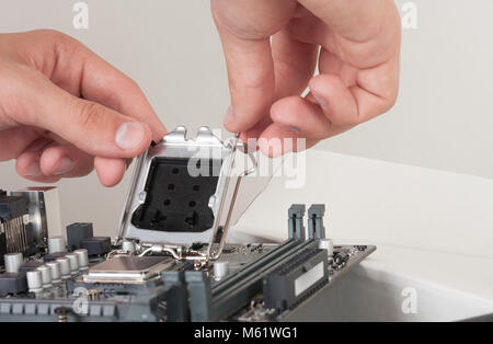 Close up of man hand closing slot for CPU on PC  motherboard. Stock Photo