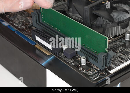 Close up of man hand with glove installing Ram DDR4 memory module in slot on motherboard.