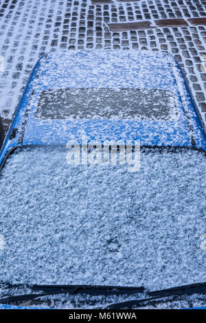 A car covered in snow and ice on a freezing morning. Defrosting the car in cold winter weather windscreen damage and in need of scraping screen to see Stock Photo