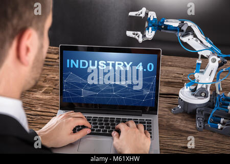 Close-up Of Businessperson Working On Design Of Industrial Robot Arm On Laptop Stock Photo