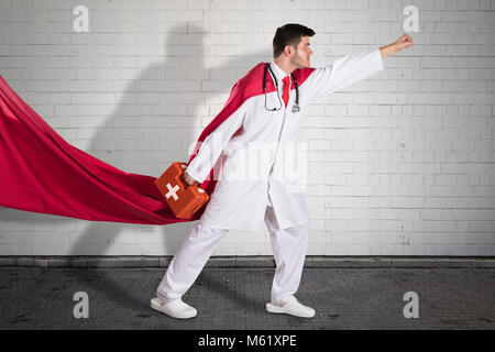 Superhero Doctor In Red Cape Carrying First Aid Box Before Flying Stock Photo