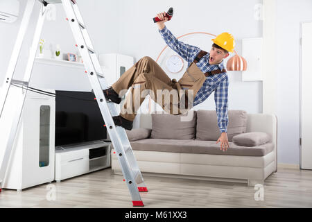 Young Male Carpenter Falling From Metal Step Ladder In Living Room Stock Photo