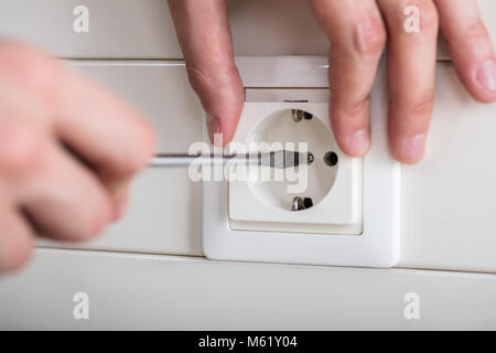 Close-up Of Person's Hand Fixing Electrical Socket With Screwdriver Stock Photo