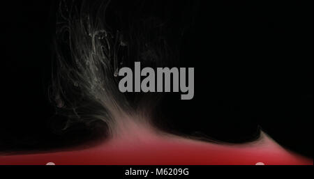 Red drops, waves and clouds of ink creating dynamic shapes in water. Abstract effects of paint colors in liquid. Studio shot on black background. Stock Photo