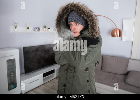 Young Man With Warm Clothing Feeling The Cold Inside House Stock Photo