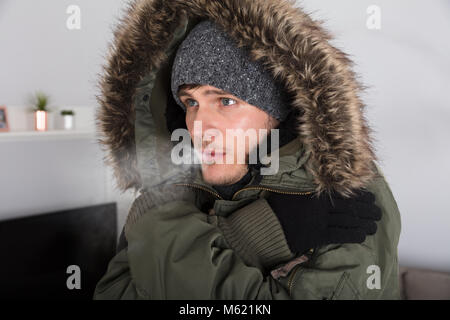 Young Man With Warm Clothing Feeling The Cold Inside House Stock