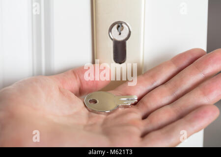 Close-up Of Person's Hand Holding Broken Key Inserting In Keyhole Stock Photo