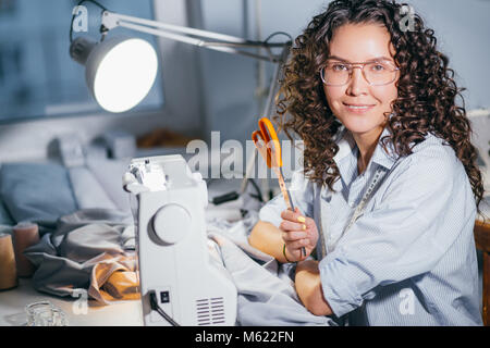 horizontal photo of tailor having big orang scissors on hand and posing Stock Photo