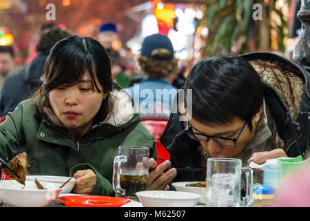 A man and woman eat Vietnamese street food, Hanoi, Vietnam. Stock Photo