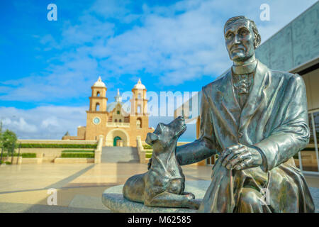 Geraldton, Australia - Dec 18, 2017: Statue of Monsignor John Hawes on foregound with St. Francis Xavier Cathedral behind on blurred background, in Geraldton, Western Australia. Sunny day. Stock Photo