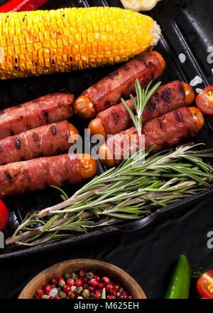 Festive cocktail sausages wrapped in crispy smoked bacon commonly known as 'Pigs in Blankets' on a black background Stock Photo