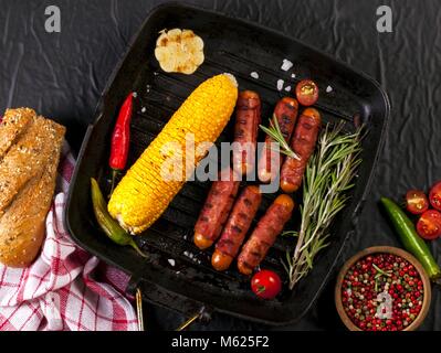 Festive cocktail sausages wrapped in crispy smoked bacon commonly known as 'Pigs in Blankets' on a black background Stock Photo