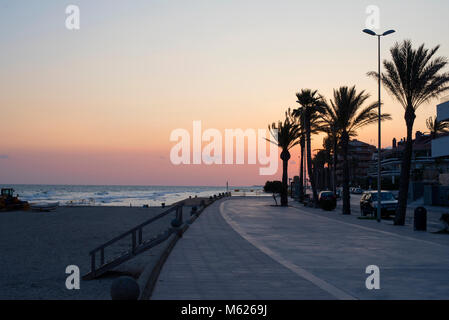 palm trees silhouetted against a colourful sunset in Sitges, southern Spain Stock Photo