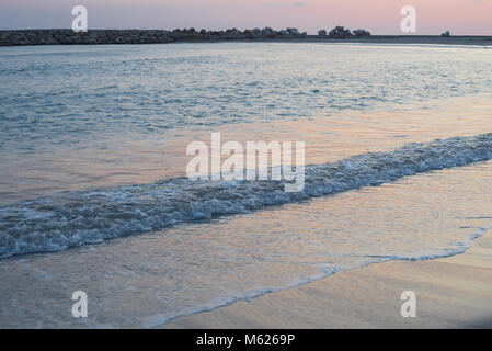 colourful sunset over waves breaking on the Spanish coast at Sitges Stock Photo