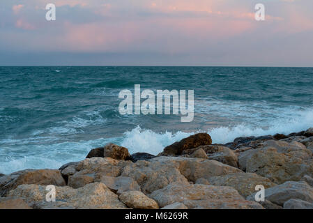 colourful sunset over waves breaking on the Spanish coast at Sitges Stock Photo