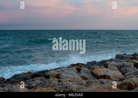 colourful sunset over waves breaking on the Spanish coast at Sitges Stock Photo