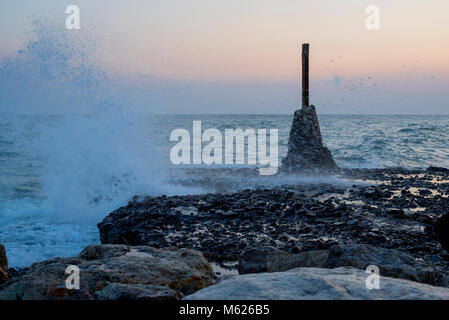 colourful sunset over waves breaking on the Spanish coast at Sitges Stock Photo