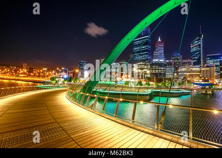 Wooden footpath of Elizabeth Quay Bridge illuminated by night at entrance of Elizabeth Quay marina, a new tourist attraction in Perth, Western Australia.Esplanade with modern skyscrapers on background Stock Photo