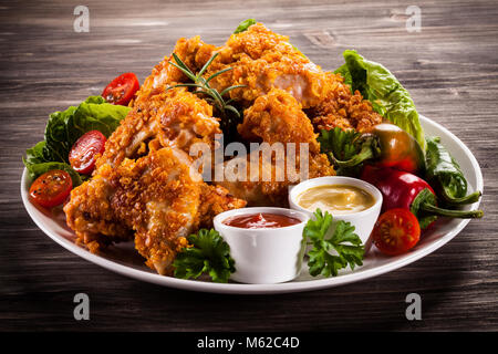 Fried chicken nuggets and vegetables on wooden background Stock Photo