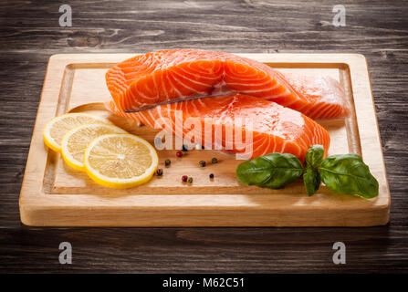 Fresh raw salmon fillets on cutting board on wooden table Stock Photo